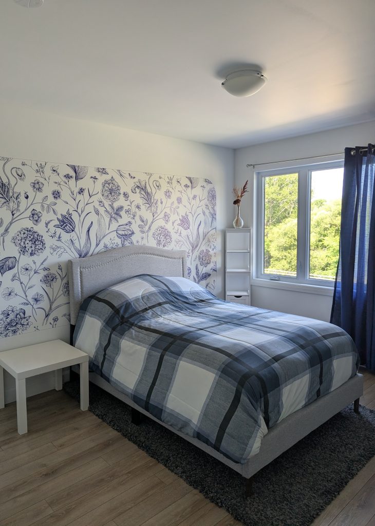 Chambre d'amis moderne transformée avec un magnifique design mural floral bleu et blanc derrière le lit.