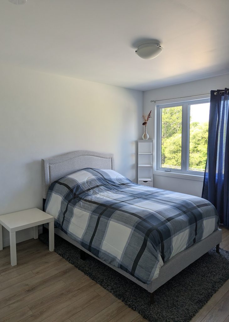 Chambre d'amis moderne transformée avec un magnifique design mural floral bleu et blanc derrière le lit.